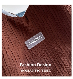 Détail macro de la texture plissée marron foncé avec écusson Fashion transparent