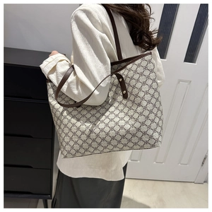 Detail view of large tote bag with retro monogram pattern and brown leather straps
