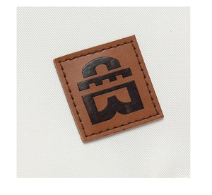 Detailed macro view of square brown leather logo patch sewn on white twill messenger bag