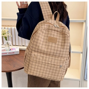 Detailed side view of the khaki plaid backpack showing fabric texture and leather logo
