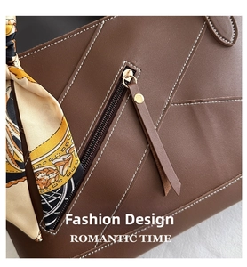 Detail of dark brown leather tote with metal zipper and stylish floral silk scarf handle