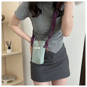 Detail of mint green corduroy mini crossbody bag with contrast purple strap and orange drawstring