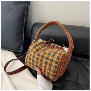 Close-up of houndstooth cylinder crossbody bag with brown corduroy and leather strap