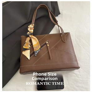 Detailed view of brown leather tote bag with contrast stitching and decorative silk scarf
