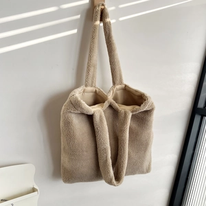 Detail of soft beige plush tote bag with lamb-like texture hanging on a wooden hook