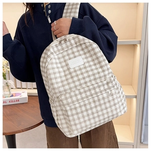Detailed side view of the plaid canvas backpack showing zipper pockets and texture