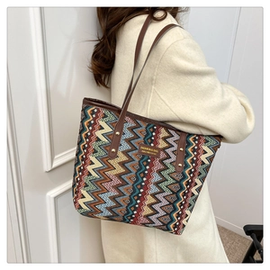 Close-up of a colorful woven ethnic tote bag with geometric wave patterns and leather handles