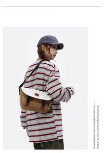 Close-up of a khaki and white contrast canvas messenger bag worn by a model in workwear style