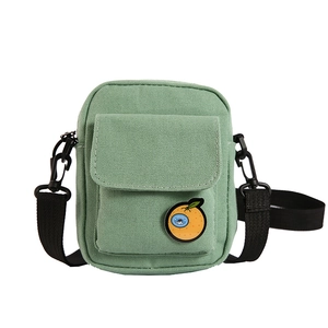 Süße hellgrüne Canvas-Umhängetasche für Damen mit Orangen-Badge und breitem schwarzem Gurt
