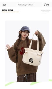Detail view of large cream tote bag with black logo and adjustable side buckle straps