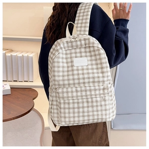 Detail of classic plaid canvas backpack with dual zippers and woven brand patch on front