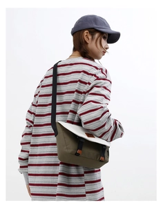 Contrast olive canvas messenger bag with white flap and adjustable strap on model