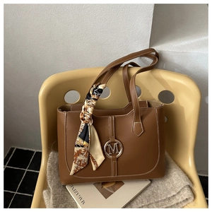 Détail d'un cabas marron avec logo M en métal et foulard en soie vintage sur la poignée