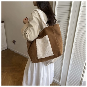 Detail of large brown suede tote bag with white faux fur pocket and strap texture