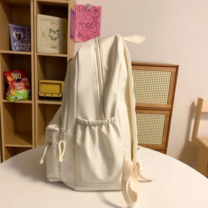 Minimalist cream nylon backpack for women with side pockets and knotted zipper pulls