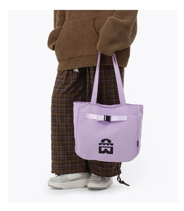 Close-up of a lilac canvas tote bag featuring buckle strap detail and geometric logo design