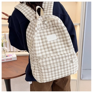 Rear view of a student wearing a beige checkered backpack in a cozy indoor setting