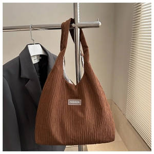 Détail d'un sac cabas marron à rayures avec texture plissée et étiquette FASHION