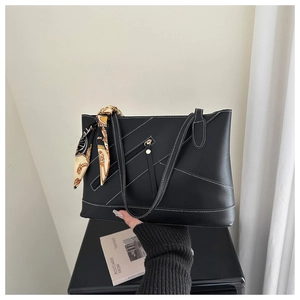 Detailed view of black tote bag with white stitching and decorative silk scarf on handle