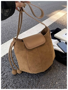 Détail du sac seau en daim marron avec fermeture à cordon et bandoulière en cuir