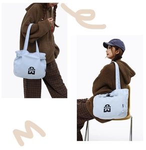 Light blue tote bag detail showing black logo design and side decorative ribbons