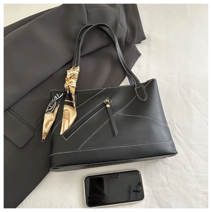 Detail of black tote bag with white contrast stitching, silk scarf and phone for size