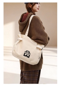 Detail shot of large canvas tote bag with black geometric logo and reinforced wide strap
