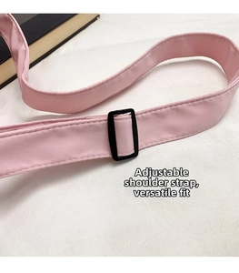 Detail of adjustable pink woven shoulder strap with black buckle for crossbody bag