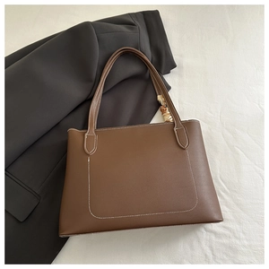 Detail of a brown leather tote bag with white contrast stitching and reinforced shoulder straps