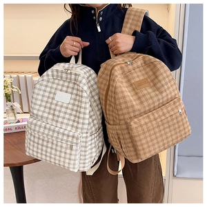 Close-up of corduroy plaid backpacks with leather logo patches and side pockets