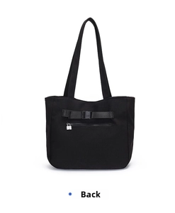 Detailed view of black tote bag back featuring security buckle and zipper pocket