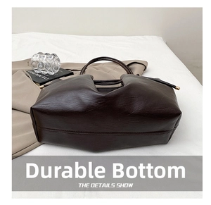 Detailed view of the durable bottom base and soft matte leather of the dark brown tote bag