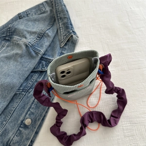 Green corduroy mini crossbody phone bag with purple ruffled strap and orange snap button