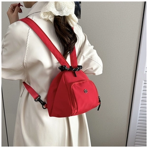Detail of red nylon mini backpack showing smooth texture and woven decorative rope
