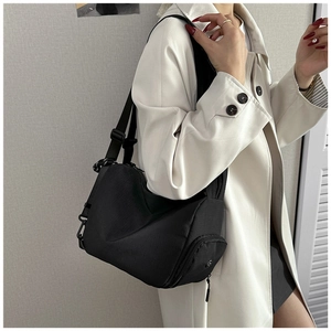 Close-up of adjustable nylon strap and side zipper pocket on black crossbody bag