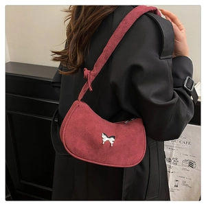 Detail of burgundy suede shoulder bag featuring a silver butterfly metallic buckle