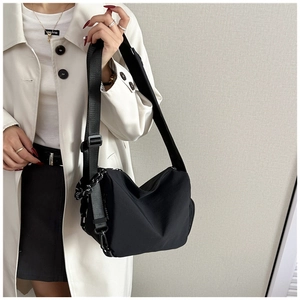 Detailed side view of black nylon crescent crossbody bag with adjustable wide strap