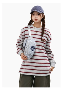 Gros plan d'un sac bandoulière gris clair avec logo EB brodé en bleu sur un mannequin