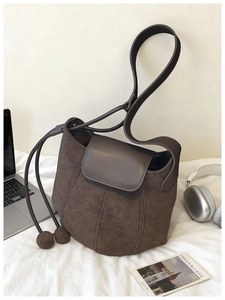 Détail du sac seau vintage en daim marron avec pendentif boule et cordon de serrage