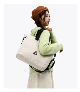 Dettaglio della borsa tote in nylon beige con logo nero indossata da una modella