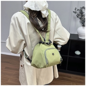 Close-up of avocado green nylon mini backpack with drawstring and U-shaped pocket