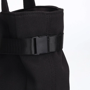 Minimalist black canvas tote bag with plastic buckle closure and nylon strap details