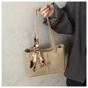 Detail van beige tote bag met metalen M-logo en decoratieve sjaal met bloemenprint