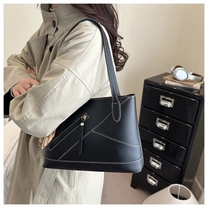 Detail of black leather tote bag with white contrast stitching and decorative silk scarf