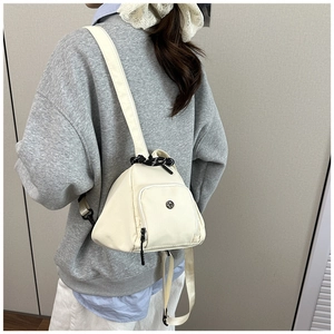 Detail view of white nylon triangular crossbody bag with black drawstring closure on model