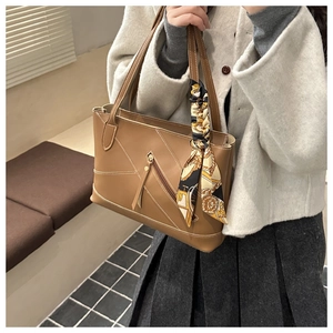 Close-up of brown tote bag with white stitching and decorative silk scarf on handle