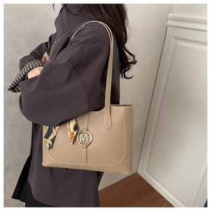 Zijaanzicht van kaki tote bag met gouden M-gesp en decoratieve sjaal op schouder