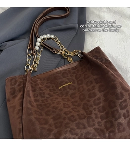 Detailed view of leopard print tote bag with gold chain and white pearl accessory