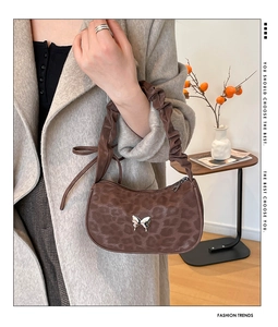 Macro shot of brown leopard print hobo bag with silver butterfly buckle and scrunched handle