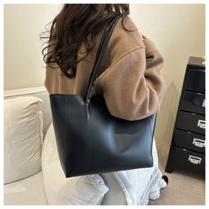 Détail du grand sac cabas en cuir noir avec fines anses pour un style chic au quotidien